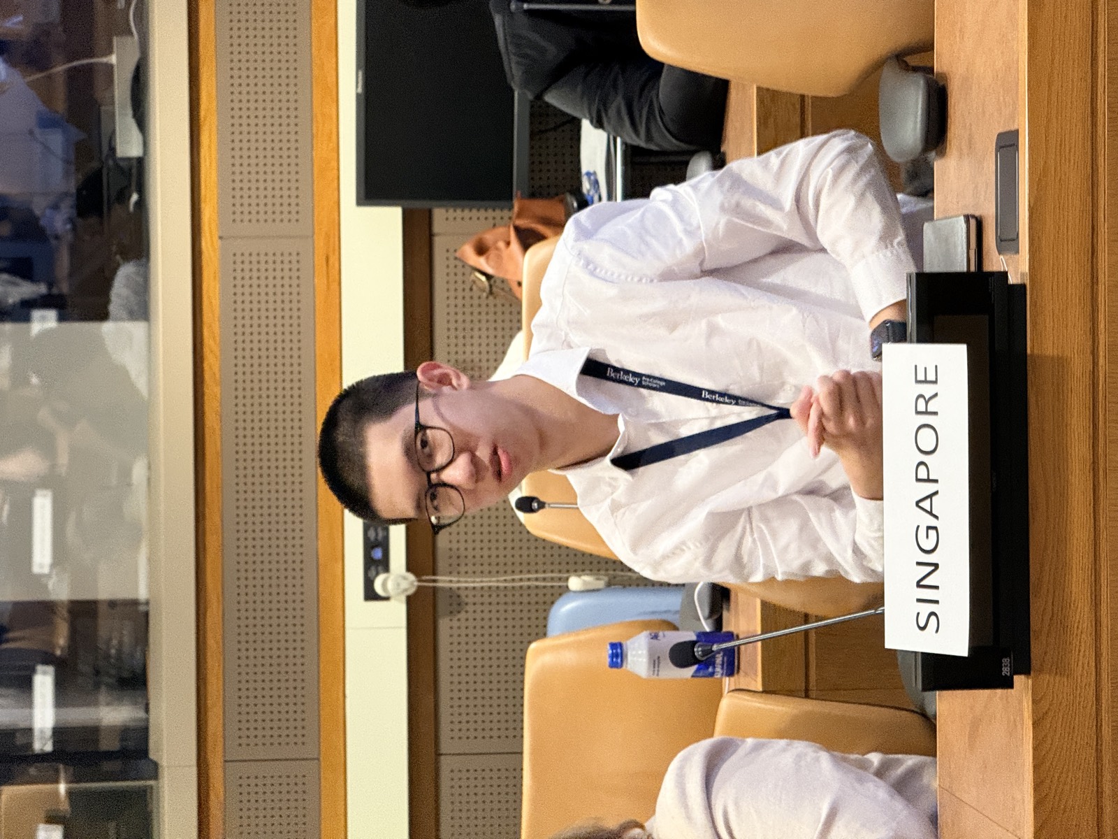 Yian Xie seated at a delegate desk in a UN conference room, behind a nameplate reading Singapore, with a microphone in front of him.